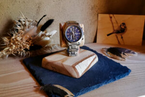 Vue avec montre du présentoir Näver en bois de bouleau massif avec son écorce préservée.